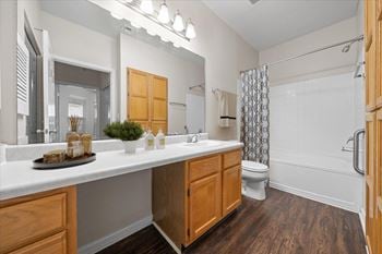 A bathroom with a white countertop and wooden cabinets.